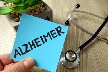 Alzheimer kelimesi mavi yapışkan nota elle yazılmış.