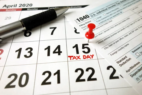 USA tax due date marked on calendar - 15 April 2020, blank 1040 form and pen