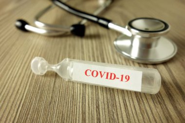 Aşı ve steteskop için kullanılan Covid-19 metni ile Ampul, yeni Coronavirus 2019 pandemik tedavi kavramı