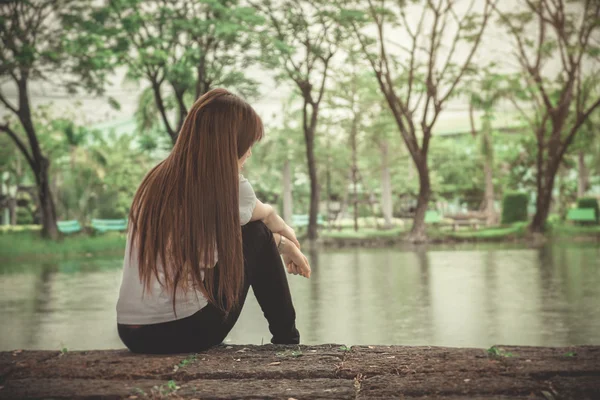 Samotna kobieta siedzi na drewniane są Lonely — Zdjęcie stockowe
