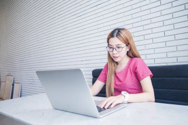 Asyalı kız cep telefonu ile oturup bir kahve dükkanında çalışan bir