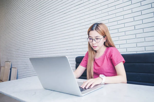 Asyalı kız cep telefonu ile oturup bir kahve dükkanında çalışan bir