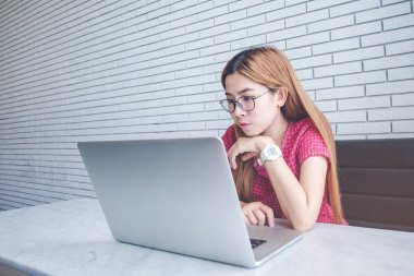 Asyalı kız cep telefonu ile oturup bir kahve dükkanında çalışan bir