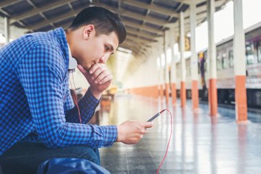 Tablet ve telefon üzerinde sta tren bekliyorsun kullanan seyahat adam