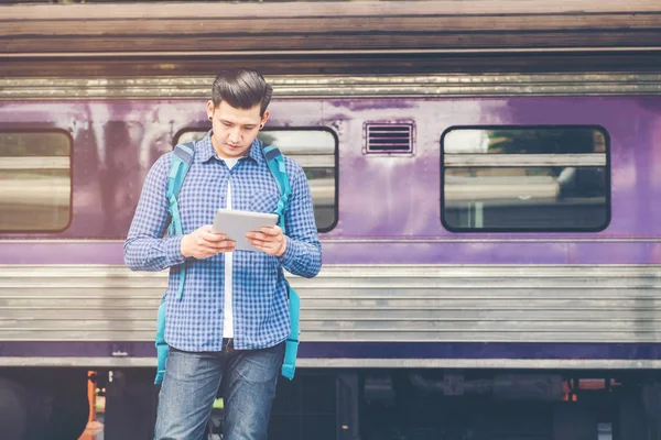Tablet ve telefon üzerinde sta tren bekliyorsun kullanan seyahat adam