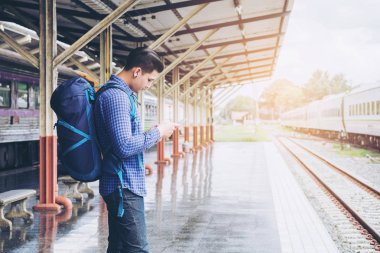 Tablet ve telefon üzerinde sta tren bekliyorsun kullanan seyahat adam