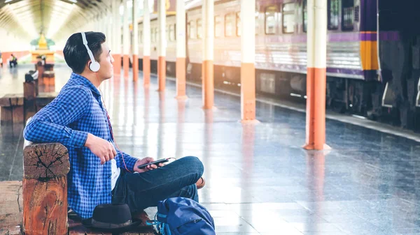 Ταξιδιώτης άνθρωπος χρησιμοποιώντας tablet και ακουστικών σε αναμονή για το τρένο για το — Φωτογραφία Αρχείου