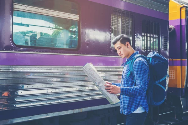 Gezgin adam harita ve beklediği tren demiryolu platformu üzerinde