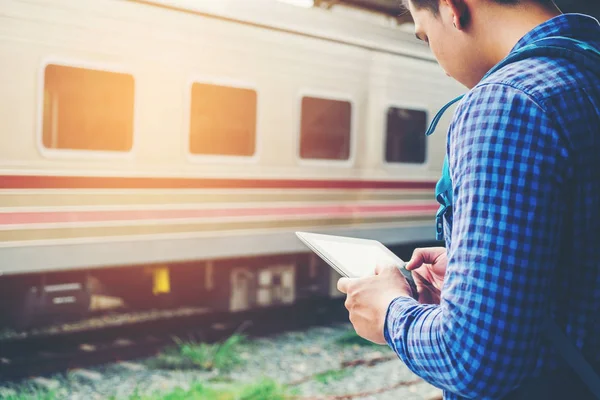 Tablet ve telefon üzerinde sta tren bekliyorsun kullanan seyahat adam