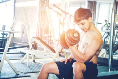 Kaslı adam atlet weightl üzerinde oturan spor salonunda çalışma dışarı inşa