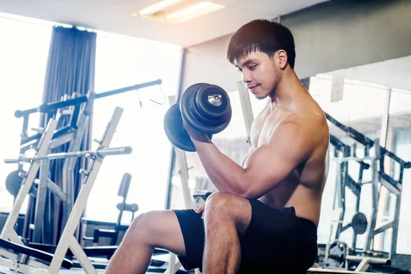 Muscular Man built athlete working out in gym sitting on weightl — Stock Photo, Image