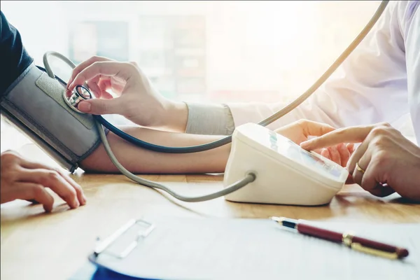 Dokter mengukur tekanan darah arteri wanita pasien di lengan. — Stok Foto