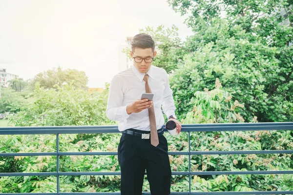 Empresário usando telefone celular mão segurando copo de café ao ar livre — Fotografia de Stock
