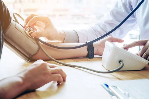 Доктор Вимірювання артеріального кров'яного тиску жінка пацієнт на руці Він — стокове фото
