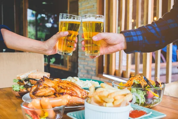 Joven bebiendo cerveza y beber vasos felices mientras disfruta de h — Foto de Stock