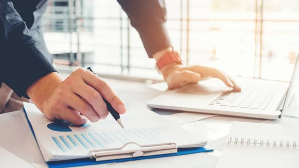 Geschäftsmann mit Laptop mit Berichtstabelle in der Büroplanung n — Stockfoto