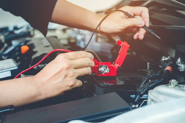 Las manos comprueban la batería del coche mecánico que trabaja en el servicio de reparación de automóviles —  Fotos de Stock