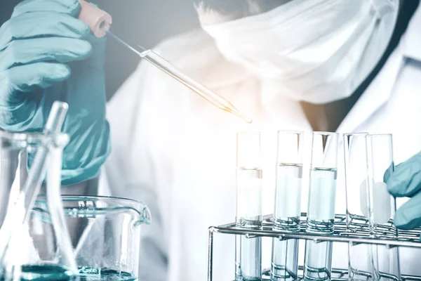 Wetenschapper chemische vloeistof daalt tot kolf in lab glas laborat — Stockfoto