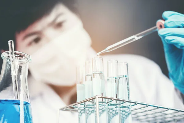 Wetenschapper chemische vloeistof daalt tot kolf in lab glas laborat — Stockfoto