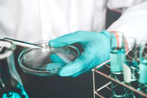 Wetenschapper dropping chemische vloeistof petrischaal in lab glas la — Stockfoto
