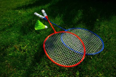 Güneşli parlak yeşil çimen taze backg üzerinde iki badminton raket