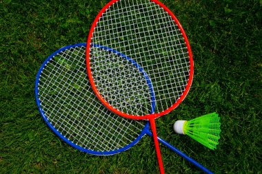 Güneşli parlak yeşil çimen taze backg üzerinde iki badminton raket