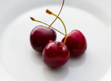 Beyaz bir plaka üzerinde üç kiraz meyve. Kiraz olgun lezzetli fru