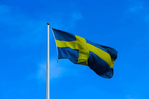Swedish flag wave on the blue sky. National symbol of Scandinavi