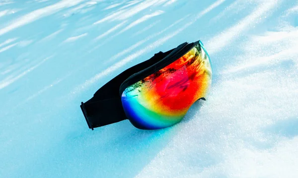 Colorful bright snowboard mask lay on the snow, winter, sunny weather.