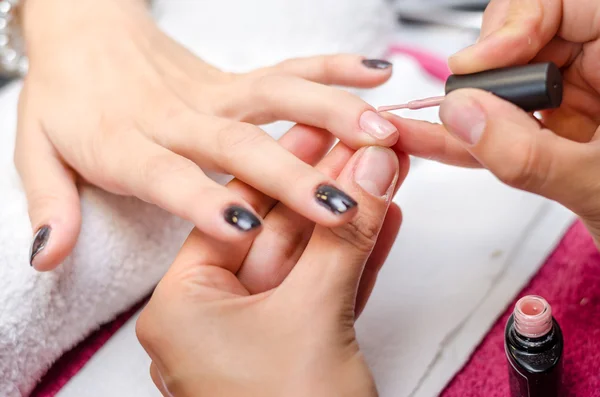 Mujer aplicando esmalte de uñas rosa — Foto de Stock