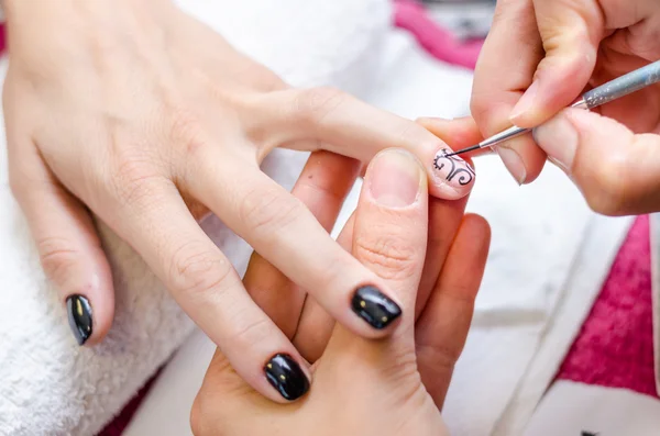 Mujer aplicando esmalte de uñas dibujo negro — Foto de Stock