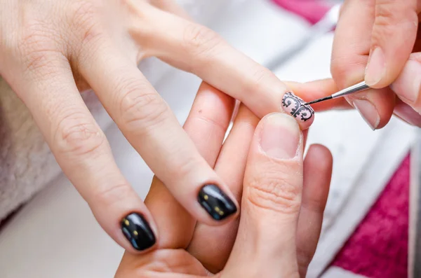 Mujer aplicando esmalte de uñas dibujo negro — Foto de Stock