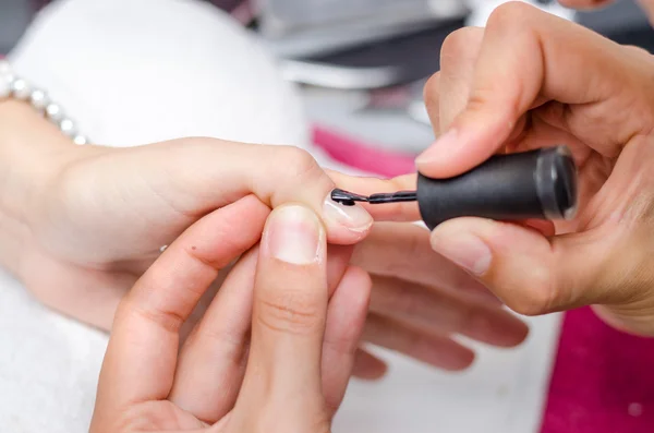 Mujer aplicando esmalte de uñas negro — Foto de Stock