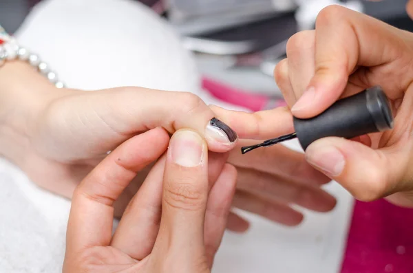 Mujer aplicando esmalte de uñas negro — Foto de Stock