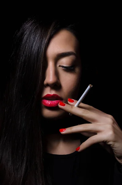 Портрет красивой элегантной девушки, курящей сигарету на черном фоне . — стоковое фото