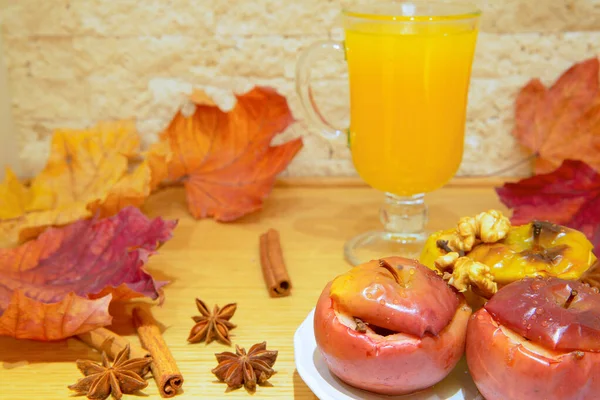 Homemade warm autumn drink beverage and tasty baked apples with cinnamon and spices. Dried fall colorful leaves.