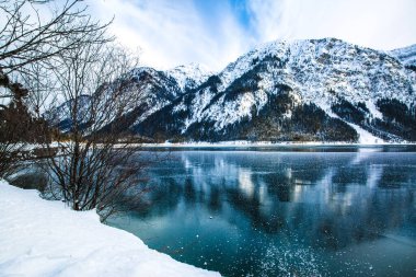 Kış gölü ve dağlarının parlak yeşil suları, Almanya, Bayern sularına yansıyor.. 