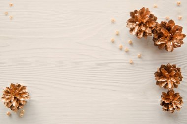 Bej arka planda altın kozalaklar, metin için boşluk, kopyalama alanı. Noel arkaplanı.