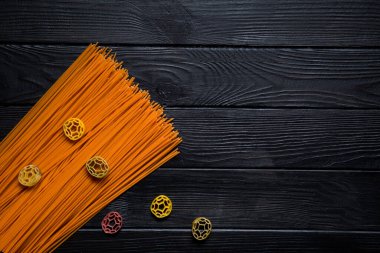 Baharatlı spagetti ve siyah ahşap arka planda farklı türde makarna.. 