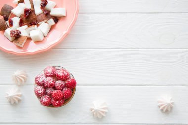 Beyaz masa üzerinde canlı mercan rengi tabakta pembe tatlılar ve hindistan cevizi parçaları, metin için boşluk, kopyalama alanı. 