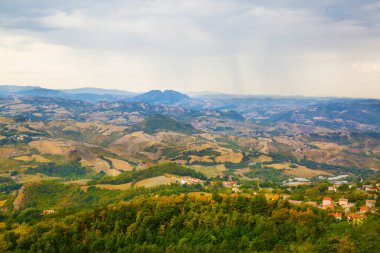 San Marino 'nun panoramik manzarası. Turuncu çatısı olan yeşil vadi. Yazın bulutlu gökyüzü. 
