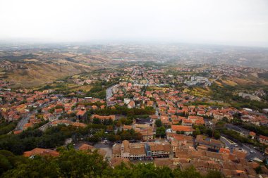 San Marino 'nun panoramik manzarası. Turuncu çatısı olan yeşil vadi. Yazın bulutlu gökyüzü. 