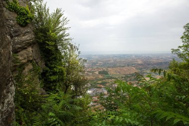 San Marino 'da. Ağaçlar yeşil vadiye kadar uzanır. İtalya, San Mariino 'ya güzel bir manzara. Kara ağır bulutlar.