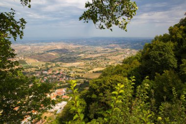 San Marino 'da. Ağaçlar yeşil vadiye kadar uzanır. İtalya, San Mariino 'ya güzel bir manzara. Kara ağır bulutlar.