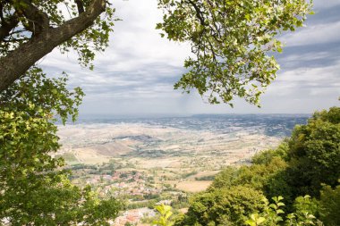 San Marino 'da. Ağaçlar yeşil vadiye kadar uzanır. İtalya, San Mariino 'ya güzel bir manzara. Kara ağır bulutlar.
