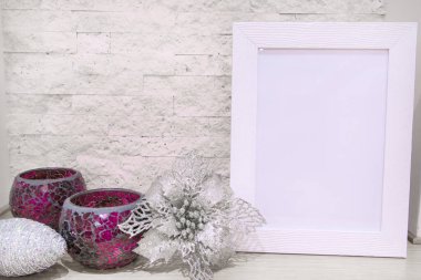 Noel çerçevesi, menekşe şamdanı ve tuğla duvarın yanında Noel gümüş süslemeleri ile süslenir. Metin için boş kopyalama alanı. 