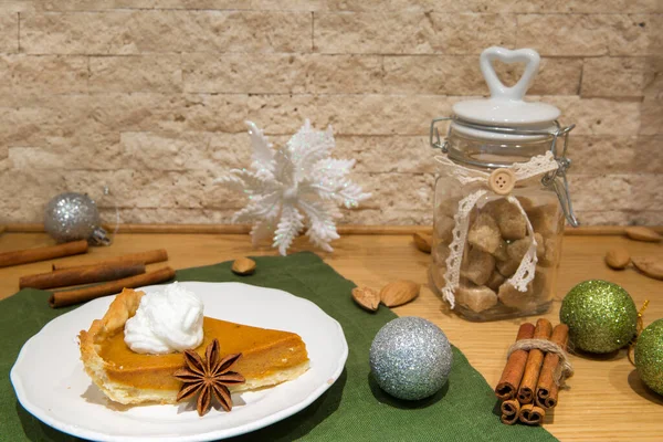 传统的美国南瓜派 带有奶油 肉桂和杏仁 圣诞绿球 红糖和雪花装饰 — 图库照片