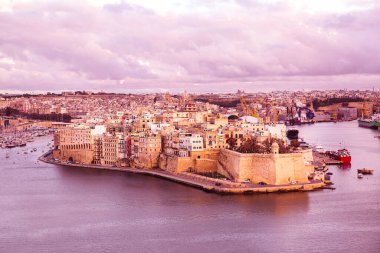 Valletta panoramik manzara, pembe günbatımının güzel renkleri. Şehir kalesi duvarları ve Akdeniz. 