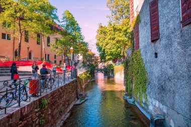 Annecy parlak renkler, Fransa. Turistler caddenin karşısındaki yeşil kanalda yürüyorlar..  