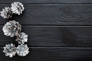 Siyah ahşap masada gümüş kozalaklar, Noel arkaplanı. Metin için boşluk, kopyalama alanı. Üst görünüm. 